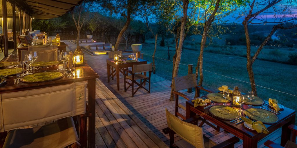 View of Entim Camp situated along the Mara River, featuring luxurious tented accommodations with stunning vistas of the expansive Masai Mara landscape, highlighting the camp's prime location for wildlife viewing and the annual wildebeest migration.